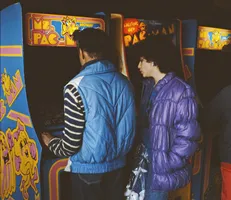deux personnes jouent au jeu Ms. Pac-Man sur une borde d'arcade Insert Coin