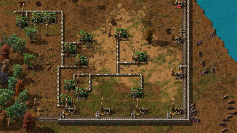 Champ pétrolier de Factorio avec plusieurs pompejacks reliés par des tuyaux et protégés par un mur